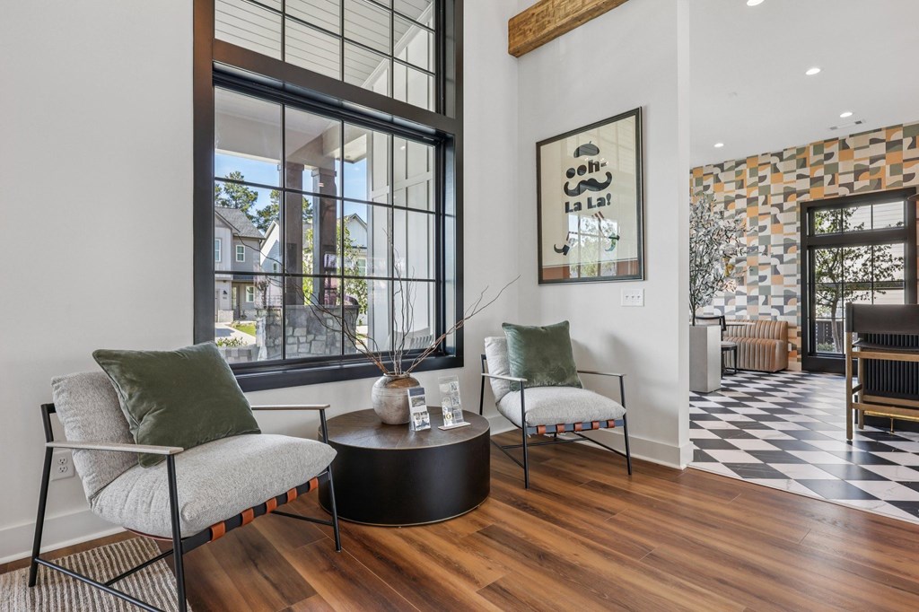 A living room with a green pillow on a chair and a coffee table in front of a window.