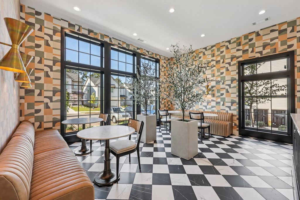 A room with a black and white checkered floor, a brown leather couch, and a tree in a white planter.