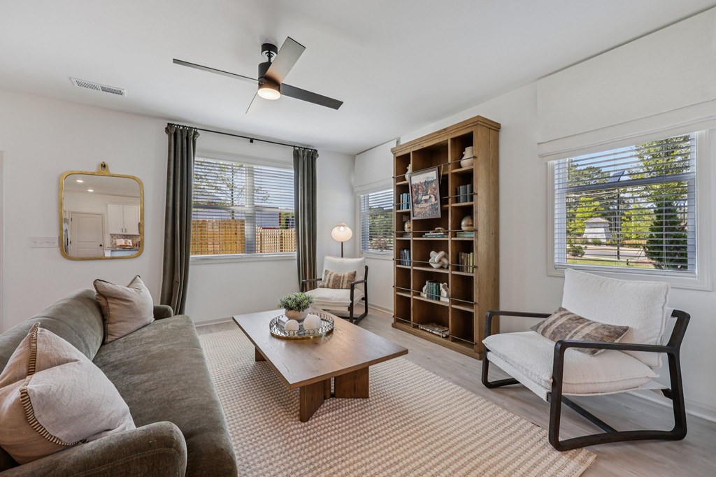 A living room with a grey couch, a wooden coffee table, a chair, and a bookshelf.