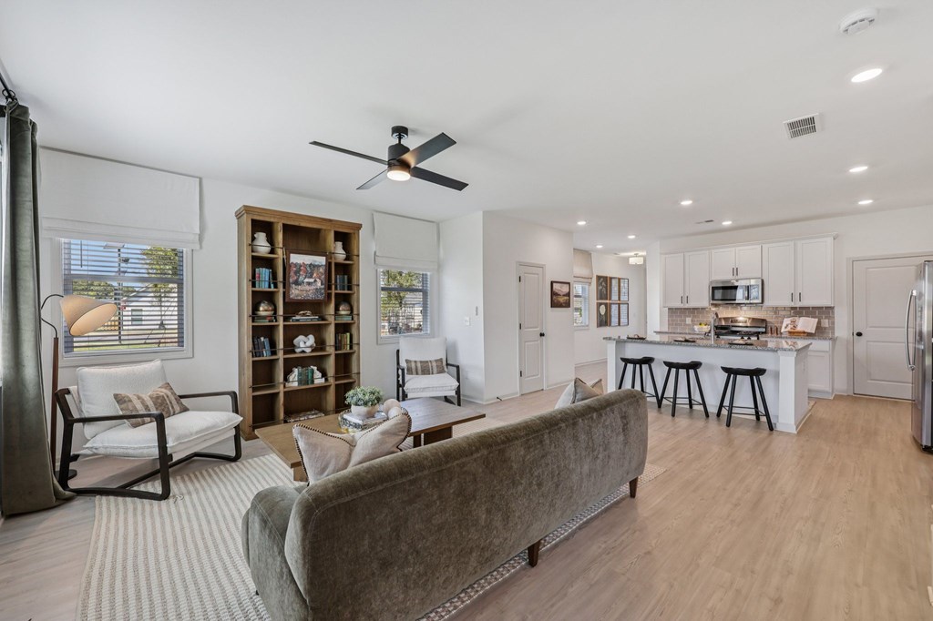 A living room with a grey couch and a ceiling fan.