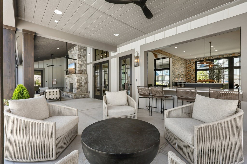 A modern outdoor seating area with white wicker chairs and a black coffee table.