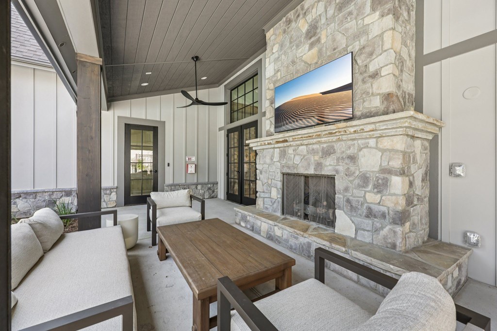 A modern living room with a stone fireplace and a flat screen TV mounted above it.