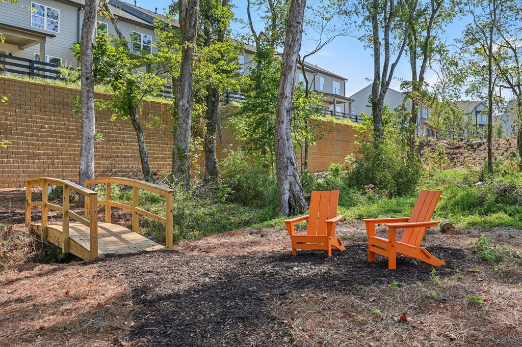 Two orange chairs are placed on a dirt ground.
