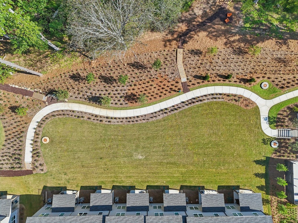 A large grassy area with a winding path and apartment buildings in the background.
