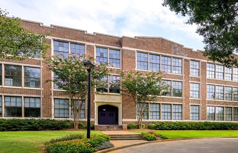 A building with a black door and windows with trees in front.