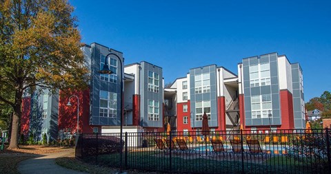 A modern building with red and grey exterior and a playground in front.