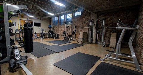 A gym with a variety of equipment including a punching bag, weight machines, and a treadmill.