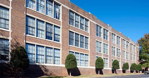 A long brick building with many windows and trees in front.
