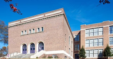 A red brick building with a blue door and windows.