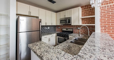 A kitchen with a granite countertop and stainless steel appliances.