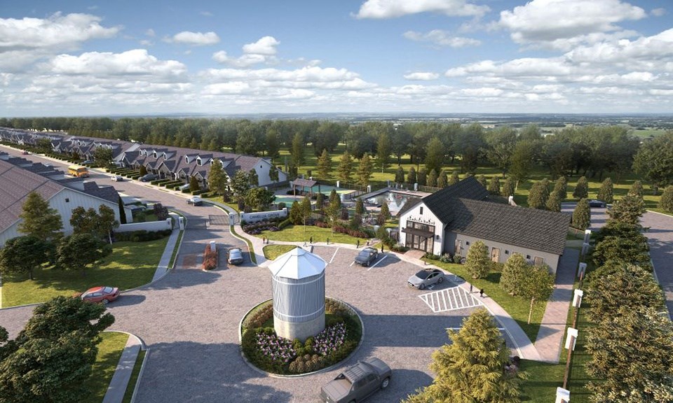 A bird's eye view of a residential area with a central roundabout and houses on both sides.