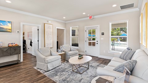 A living room with white furniture and a painting on the wall.