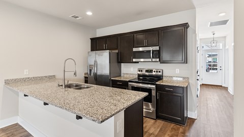 A kitchen with granite countertops and dark brown cabinets.