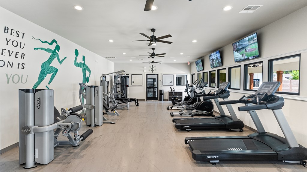 A gym with treadmills, exercise bikes and a wall mural that says "Best you ever".