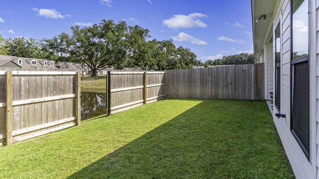 A backyard with a wooden fence and a green lawn.