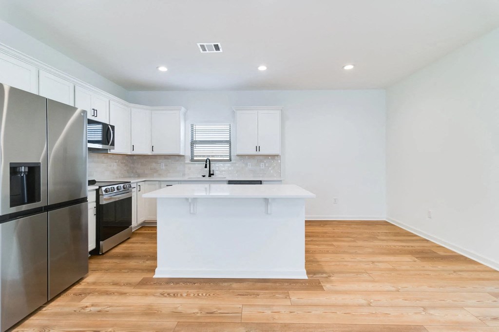 A modern kitchen with wooden floors and stainless steel appliances.