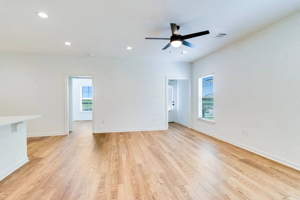 A spacious room with wooden flooring and a ceiling fan.
