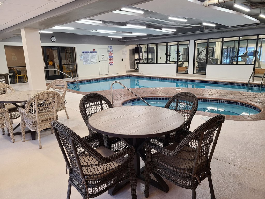 a round table and chairs next to a swimming pool