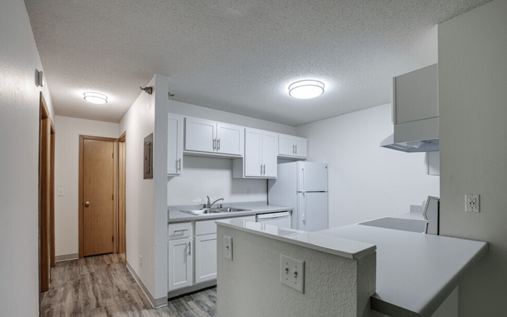 an empty kitchen with white cabinets and a white refrigerator and sink