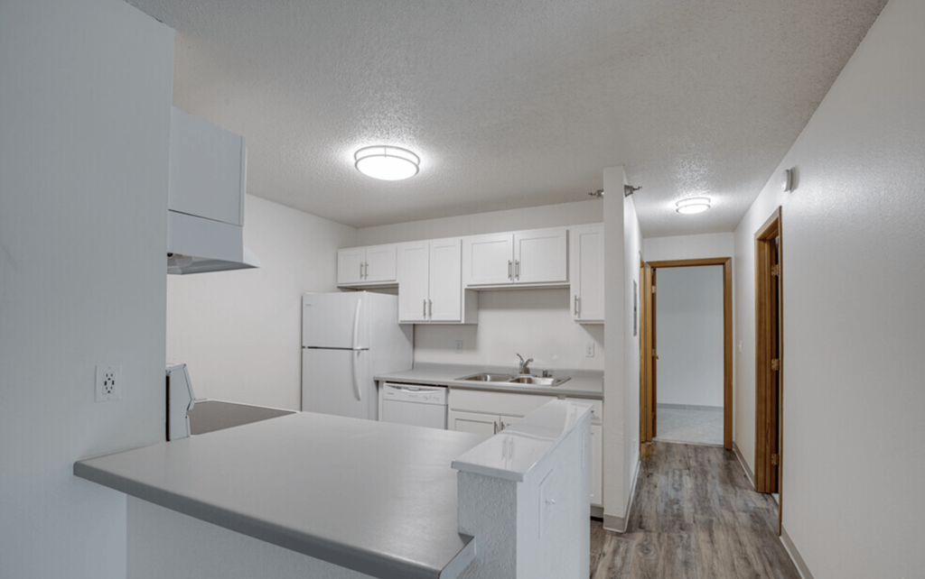 an empty kitchen with white cabinets and a white refrigerator and sink