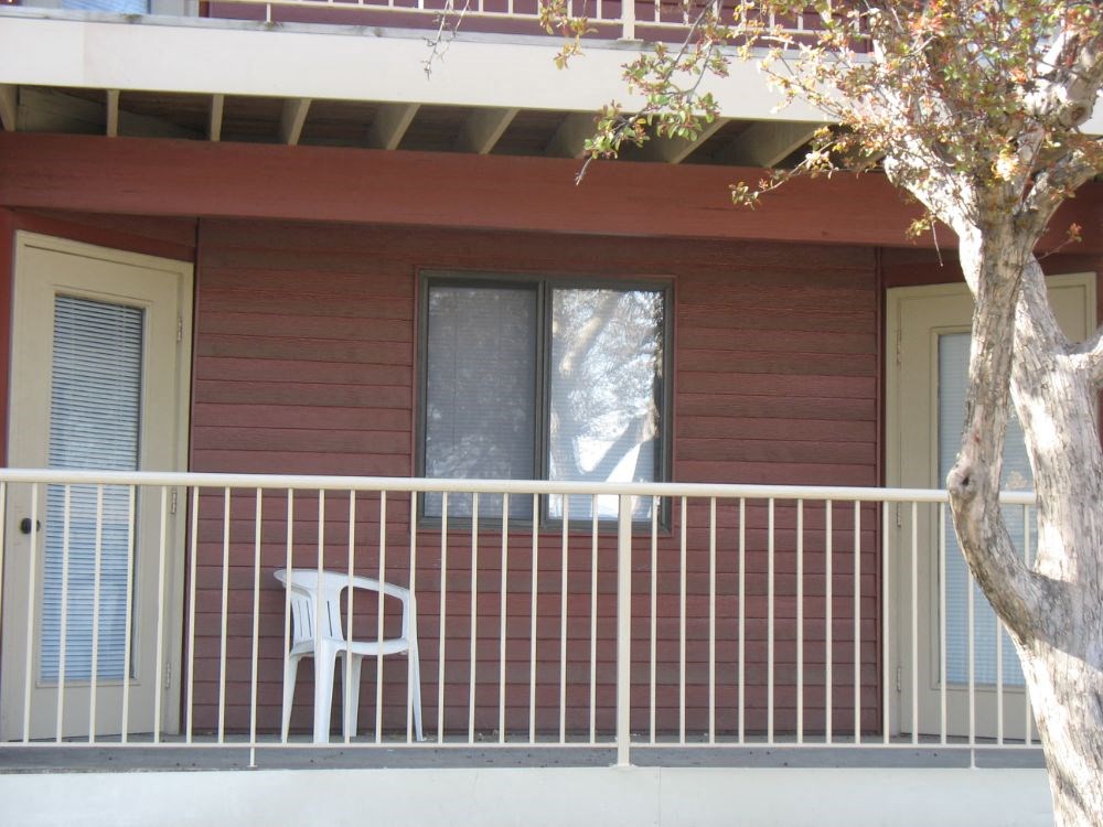 a white chair on the balcony of a red house
