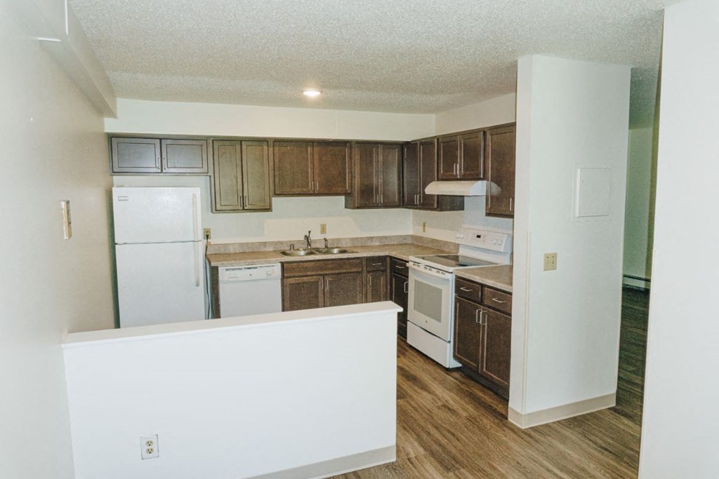 an empty kitchen with white appliances and wooden cabinets