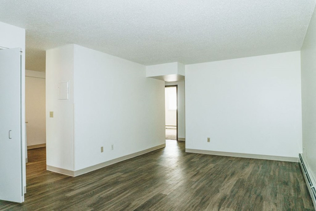 an empty living room with white walls and wood floors