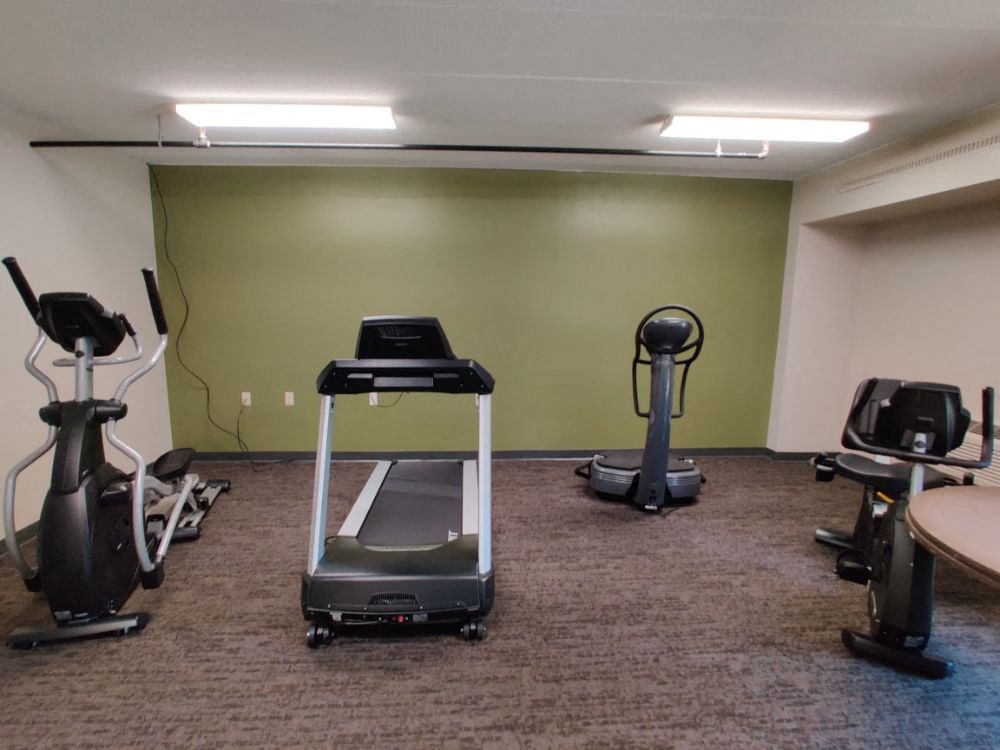 a workout room with treadmills and other exercise equipment