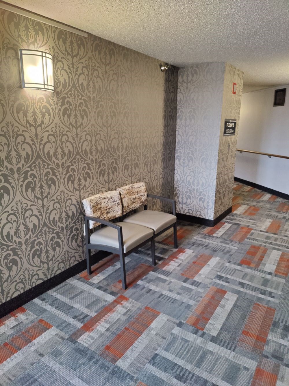 a lobby with a chair and a wall with a door
