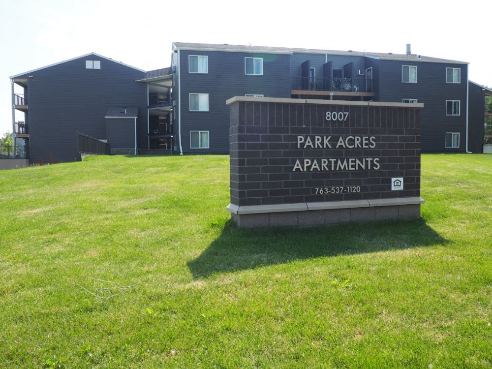 a sign for park acres apartments in front of a green field