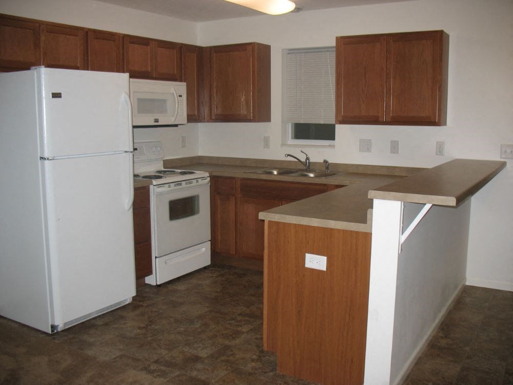 an empty kitchen with a refrigerator and a sink