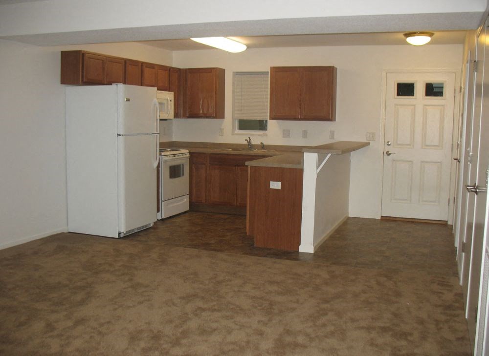 an empty kitchen with white appliances and wooden cabinets