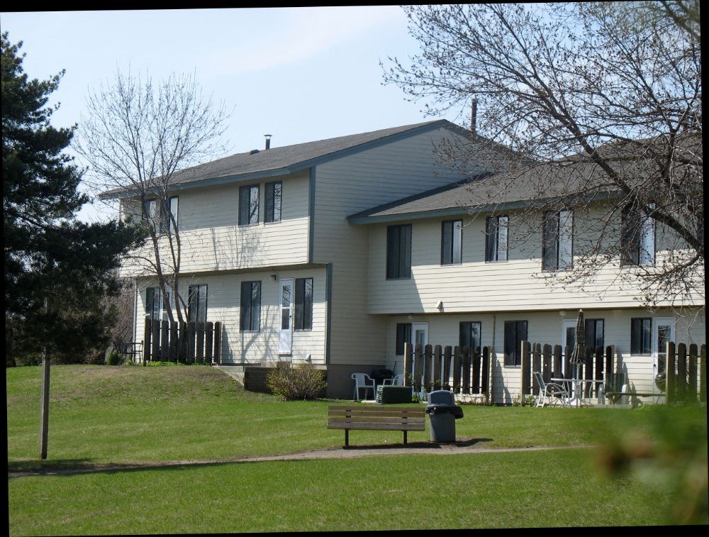 a large white house with a wooden bench in front of it