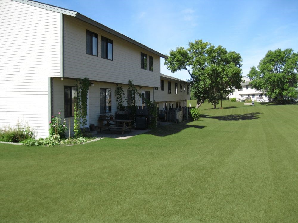 a view of the side of a white house with a green lawn