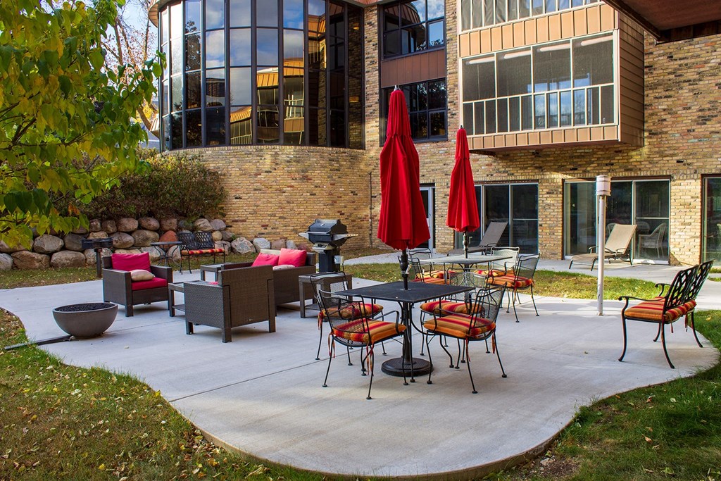 a patio with tables and chairs and umbrellas in front of a building