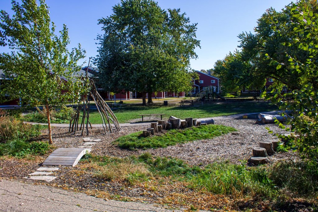 a garden with a playground and a house in the background