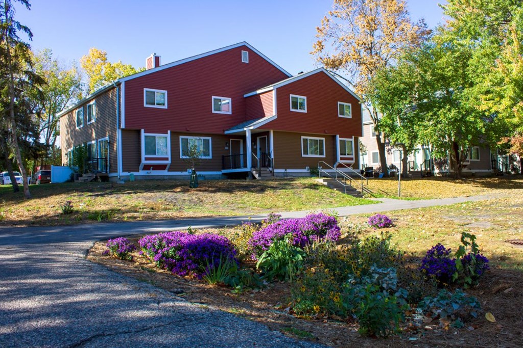 the front of a red house with a garden in front of it