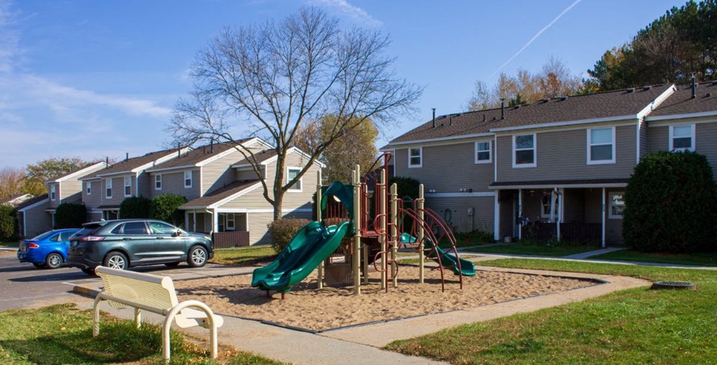 a playground in the middle of a yard in front of houses