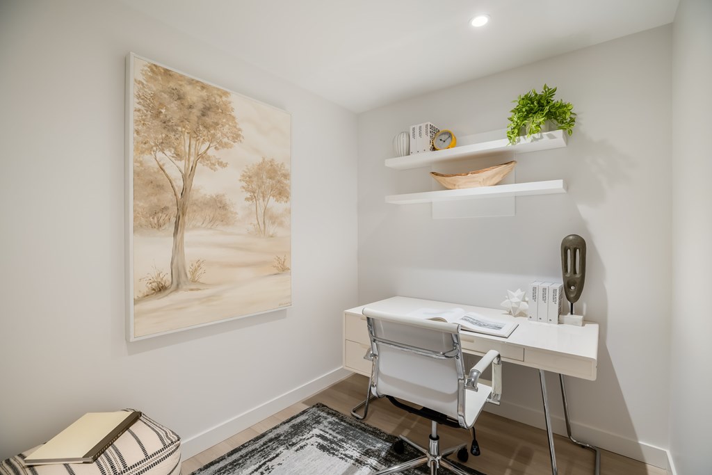 A room with a desk and a painting of trees on the wall.