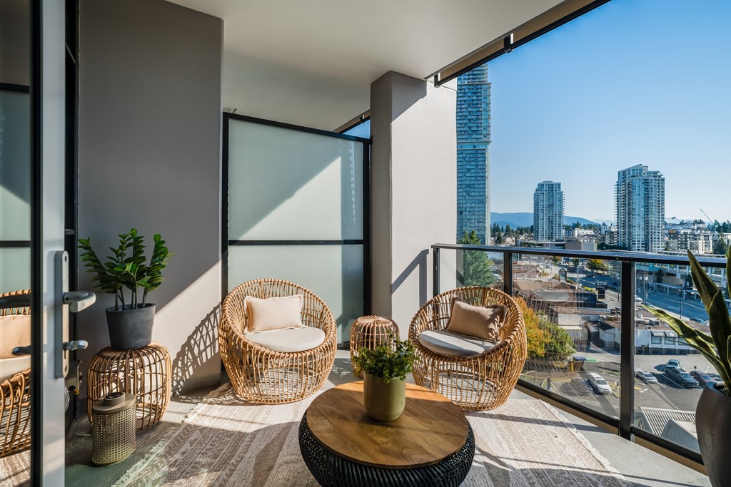 A balcony with wicker chairs and a table with a potted plant on it.