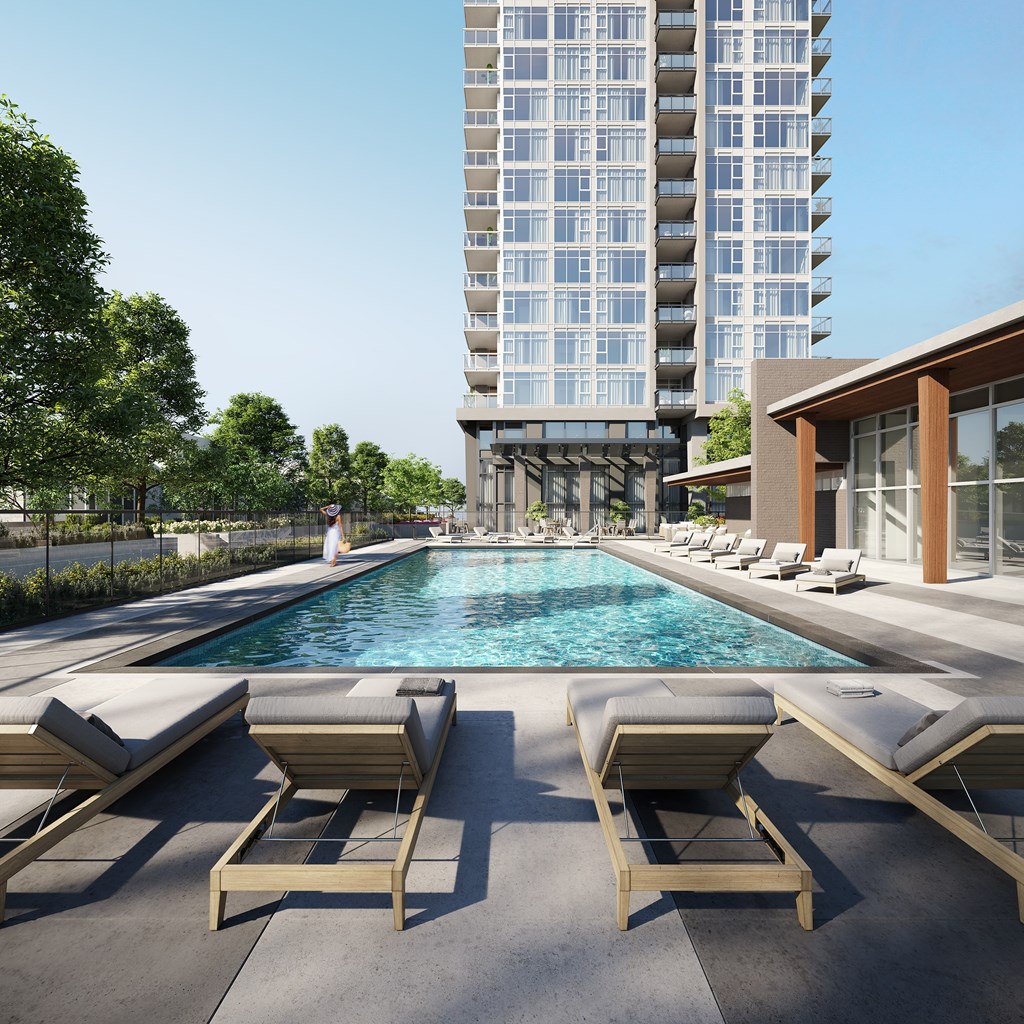 A pool with sun loungers and a building in the background.