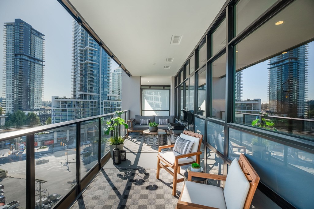 A balcony with chairs and a table overlooking a cityscape.