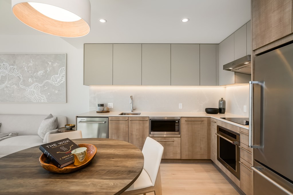 A modern kitchen with a wooden table and a book on it.