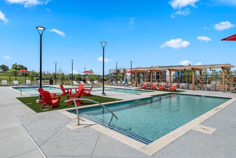 A pool area with red chairs and a wooden pergola.