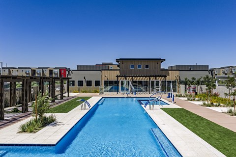 A swimming pool in front of a building with a clear blue sky.