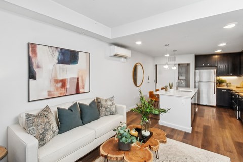 A living room with a white couch and a painting on the wall.