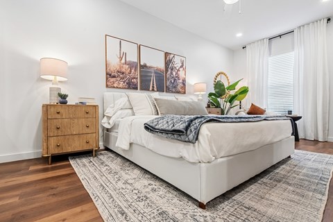 A bedroom with a large bed, a wooden nightstand, and a rug on the floor.