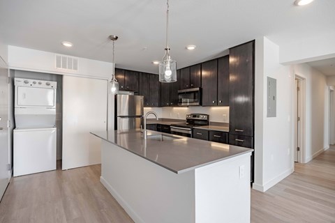 A modern kitchen with a white island and dark brown cabinets.