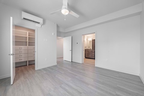 A spacious room with a ceiling fan and a cabinet with drawers.