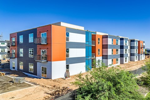 A row of modern, multi-colored apartment homes with balconies and doors.